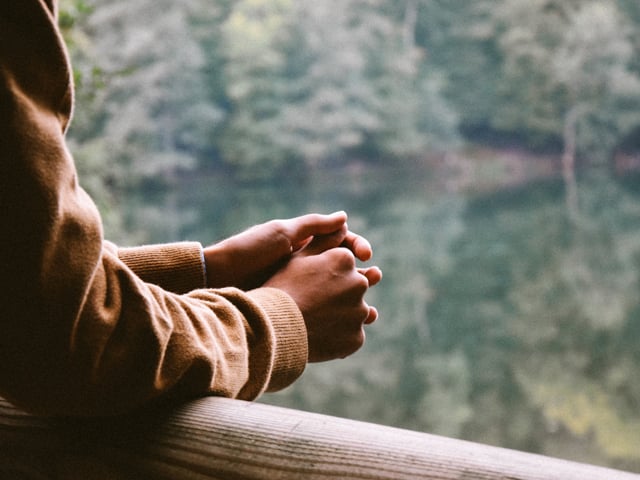 hands clasped on a rail of a cabin out in nature